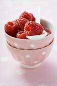 Raspberries in small pink bowl with spoon