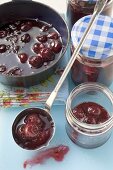 Ladling cherry jam into jars