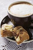 Cappuccino und kleine Stücke Schokokuchen mit Macadamianüssen