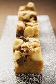 Small pieces of chocolate slice with macadamia nuts on board