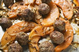 Meatballs with roasted pumpkin slices on baking tray