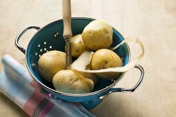 Kartoffeln, eine halb geschält, im Fussseiher