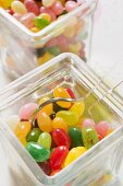 Coloured jelly beans in two storage jars (close-up)