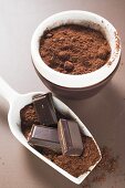Schokoladenstücke und Kakaopulver in Schaufel und Schale