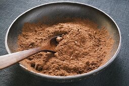 Cocoa powder in bowl with wooden spoon