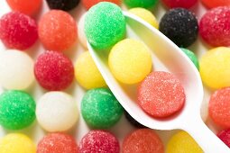 Coloured jelly sweets in rows with scoop (close-up)