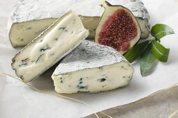 Blue cheese with pieces cut and half a fig on paper