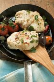 Monkfish cutlets with cherry tomatoes & olives in frying pan