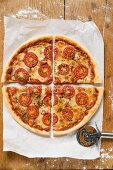 Pizza mit Tomatenscheiben, Käse und Oregano (geviertelt)