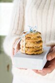 Hands holding cranberry cookies on small box