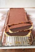 Rectangular chocolate tart with cocoa powder, a piece cut
