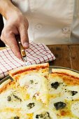 Chef serving slice of American-style three cheese pizza