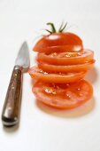 Tomate, in Scheiben geschnitten, daneben Messer