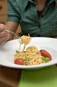 Woman behind plate of spaghetti with tomatoes and basil