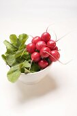 A bunch of radishes in a white bowl