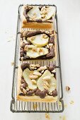 Three pieces of pear & chocolate tart with almonds on rack
