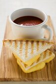 Käsetoasts und eine Tasse Tomatensuppe auf Schneidebrett