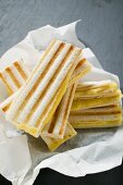 Several toasted cheese sandwiches on paper