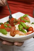 Woman eating tomatoes with mozzarella and basil