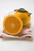 Ganze Orange mit Blatt und Orangenhälfte auf Tuch