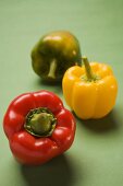 Three peppers (yellow, red, green) on green background