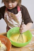 Small boy stirring cake mixture with whisk