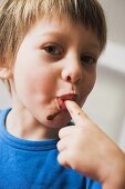 Small boy licking chocolate from his finger