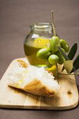 Grüne Oliven am Zweig, Weißbrot und Olivenöl