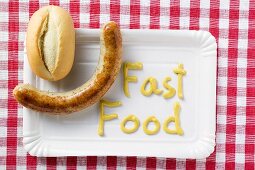 Sausage with bread roll and 'Fast Food' written in mustard