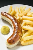 Sausage with chips and mustard on plate