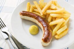 Sausage with chips and mustard on plate