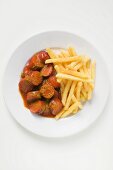 Currywurst mit Ketchup und Pommes frites auf Teller