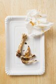 Chicken bones and paper napkin on paper plate