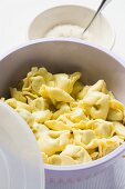 Tortellini in white bowl, grated Parmesan behind