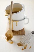 Gravy in an enamel jug, wooden spoon, whisk