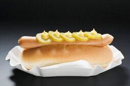 Hot Dog mit Essiggurken und Senf auf Pappteller