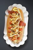 Hot dog with sauerkraut, mustard, ketchup and onions