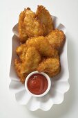 Chicken nuggets with ketchup in paper dish (overhead view)