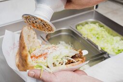 Sprinkling seasoning on a döner kebab (opened)