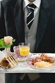 Butler serviert englisches Frühstück auf Tablett