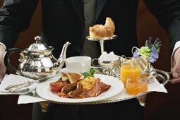 Butler serving English breakfast on tray