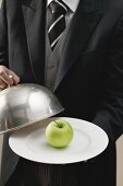 Butler serviert Apfel auf Teller mit Cloche