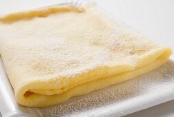 Crêpe with icing sugar on paper plate (close-up)