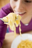 Young woman eating ribbon pasta