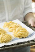 Person holding home-made pasta on wicker tray