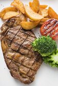 Grilled beef steak with vegetables and potato wedges