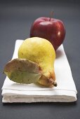 Red apple and pear with leaf on cloth