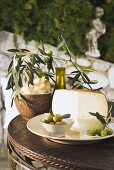 Oliven, Käse, Cracker und Olivenöl auf Tisch im Freien