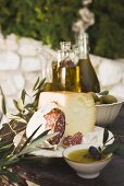 Käse, Salami, Oliven und Olivenöl auf Tisch im Freien