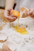 Nudelteig zubereiten: Kind schlägt Ei auf